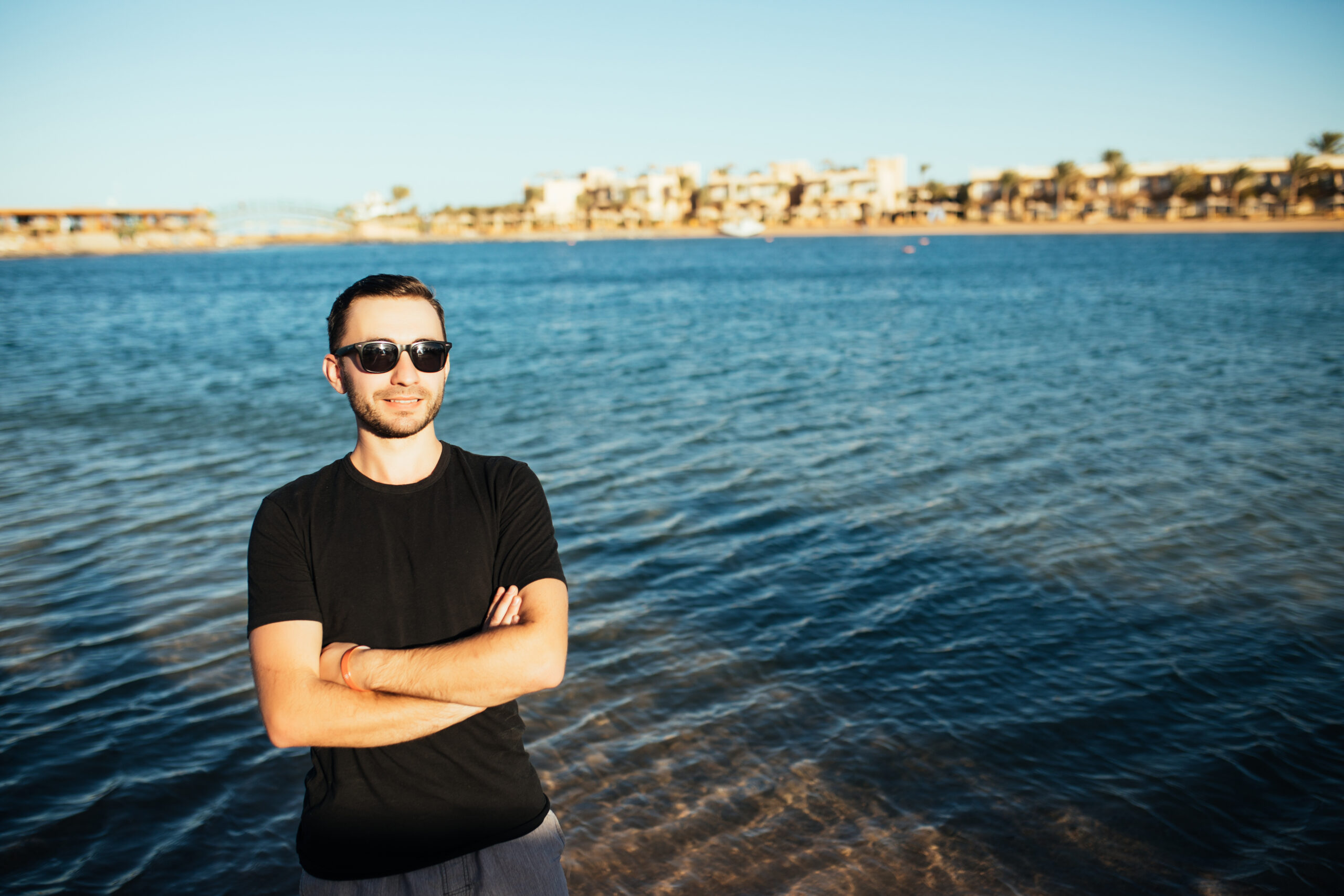 young handsome man wearing spectacles and having fun on sea beach